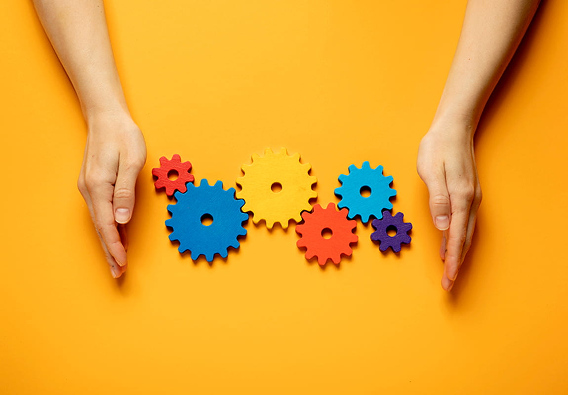 Hands surrounding coloured cogs